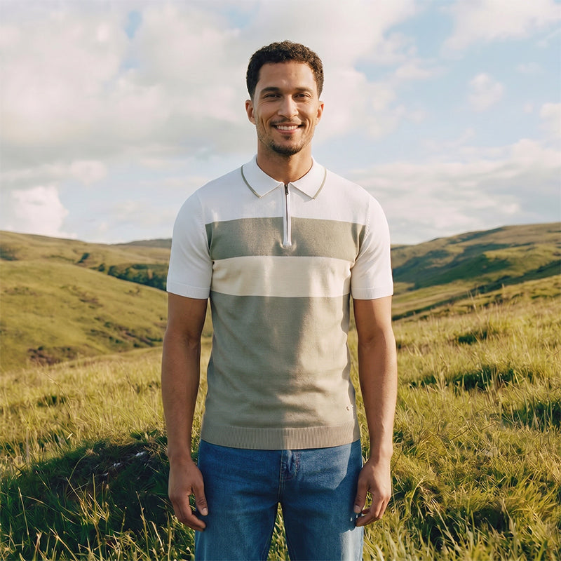 Man standing in a field with green hills and blue sky